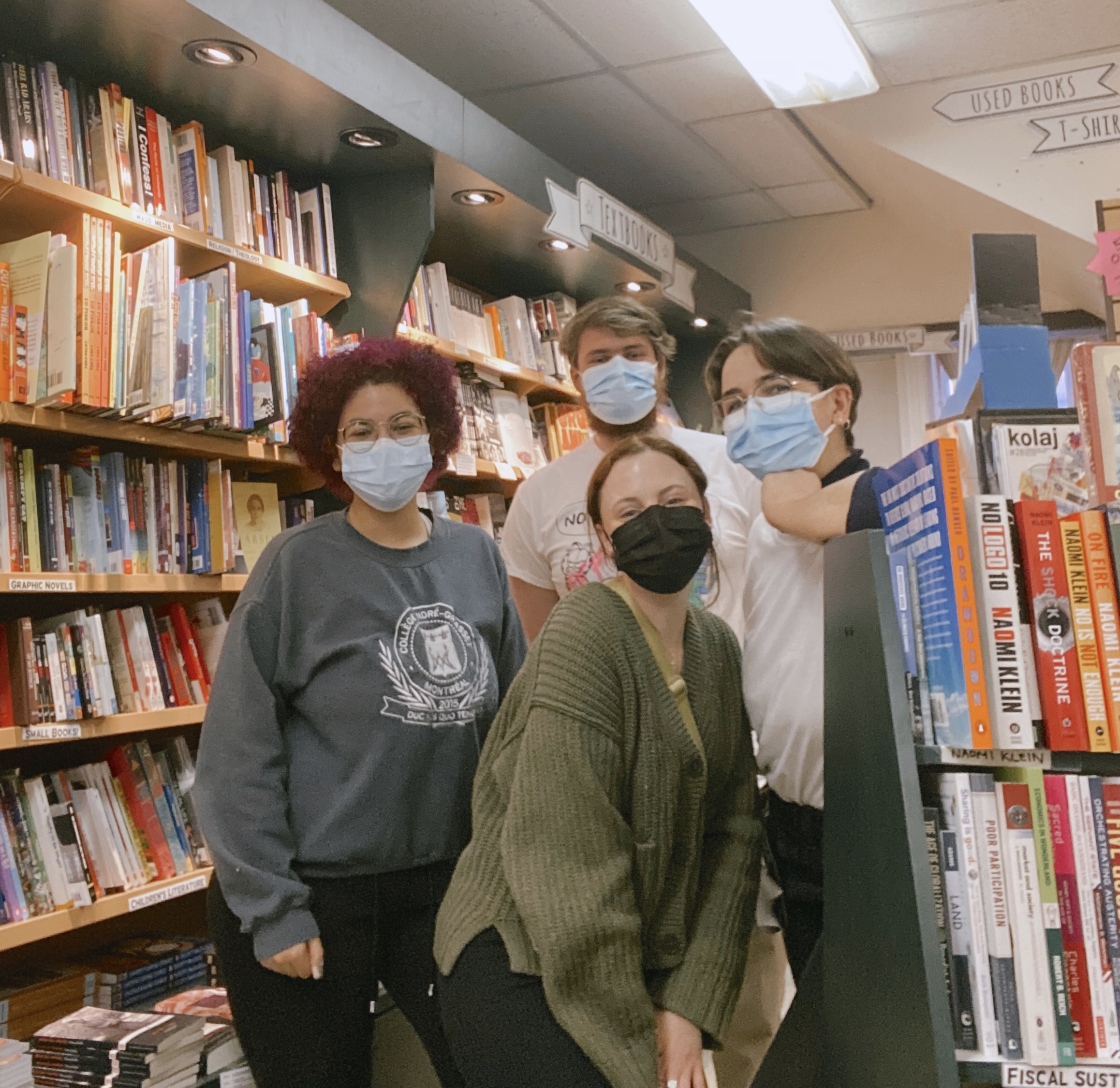 group of four people smiling in a bookstore surrounded by books.